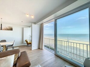 Ein modernes Wohnzimmer mit großem Balkon mit Blick auf einen Strand.