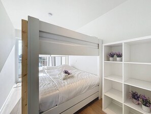 Un lit superposé avec une tête de lit blanche et une étagère blanche placée à côté.