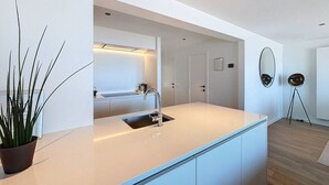 Een moderne keuken met een wit aanrecht, een gootsteen en een potplant.