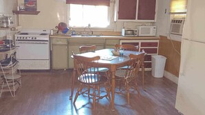 Una cocina funcional con una mesa de comedor de madera, estufa y refrigerador.