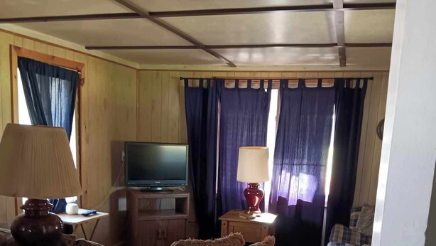 Una sala de estar acogedora con un sofá, un televisor y una lámpara.