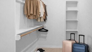 Ein begehbarer Kleiderschrank mit Kleiderstangen, Regalen und Schuhablage.