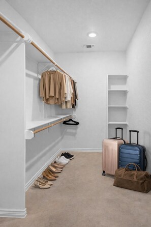 A walk-in closet with hanging clothes, shelves, and a shoe rack. - Modern Comfort Meets Convenience at Temple Twin Retreat (Temple)