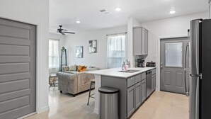 Une cuisine moderne avec des meubles gris, un îlot central et un lave-vaisselle encastré.