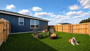 A backyard with a house, a fire pit, a dog, and a wooden fence. - Modern Comfort Meets Convenience at Temple Twin Retreat (Temple)