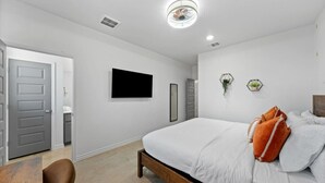 Une chambre à coucher avec un lit, une télévision, une porte et une chaise.