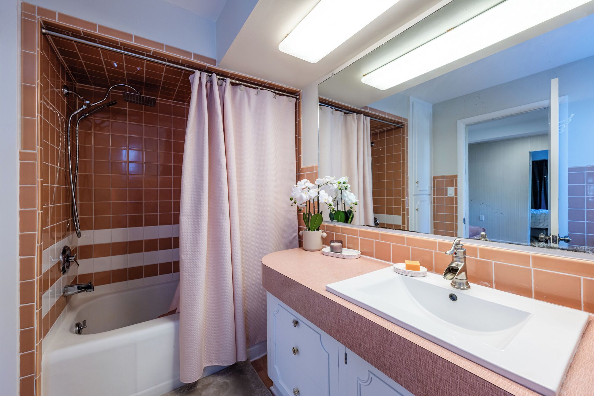 A bathroom with a bathtub, a sink, and a mirror.