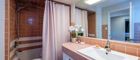A bathroom with a bathtub, a sink, and a mirror.