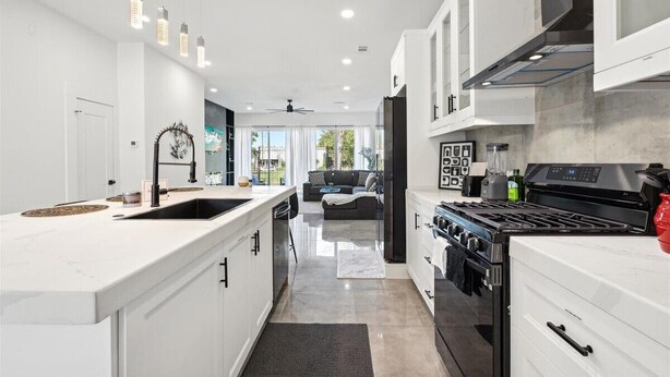 A modern kitchen with white cabinetry, a central island, and a built-in stove. - The Terrace In Dallas I Downtown Dallas I House (Dallas)
