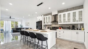 A modern kitchen with a central island, bar stools, and white cabinetry. - The Terrace In Dallas I Downtown Dallas I House (Dallas)