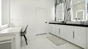 A modern bathroom with white cabinetry, a marble backsplash, and a large mirror. - The Terrace In Dallas I Downtown Dallas I House (Dallas)