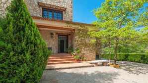 A stone building with a stone staircase leading to a door, surrounded by greenery and a well-maintained garden. - Azuara 3 Dormitorios Los Villares by Ruralidays (Jaén)
