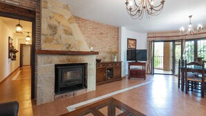 A living room with a stone fireplace, wooden furniture, and a TV. - Azuara 3 Dormitorios Los Villares by Ruralidays (Jaén)