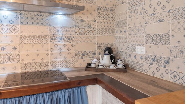 Una cocina con varios diseños de azulejos, una encimera de madera y un hervidor sobre una bandeja.