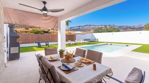 Un espace extérieur aménagé pour les repas, avec une piscine, un barbecue et une vue sur le paysage.