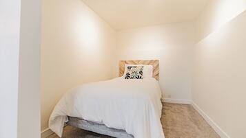 A bedroom with a single bed, a headboard with a patterned design, and a carpeted floor.