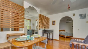 Una stanza accogliente con un tavolo da pranzo in legno, una sedia pieghevole, un letto con copriletto blu e bianco a quadri e una panca in legno.