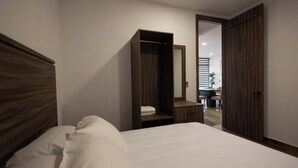 Une chambre à coucher comprenant un lit, une armoire en bois, un miroir et un bureau avec une chaise.
