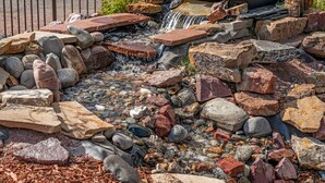 Una cascata con rocce di diverse dimensioni e un pontile in legno.