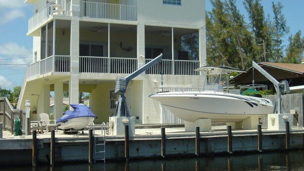 A multi-story building with balconies and a dock with a boat. - 4-bedroom Waterfront Home in Key Largo with Dock (Key Largo)