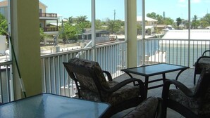 A balcony with wicker furniture and a view of the sea and buildings. - 4-bedroom Waterfront Home in Key Largo with Dock (Key Largo)