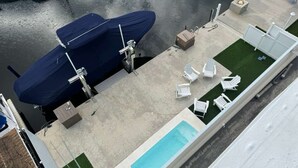 An aerial view of a rooftop pool area with a covered boat, lounge chairs, and a small deck. - 4-bedroom Waterfront Home in Key Largo with Dock (Key Largo)
