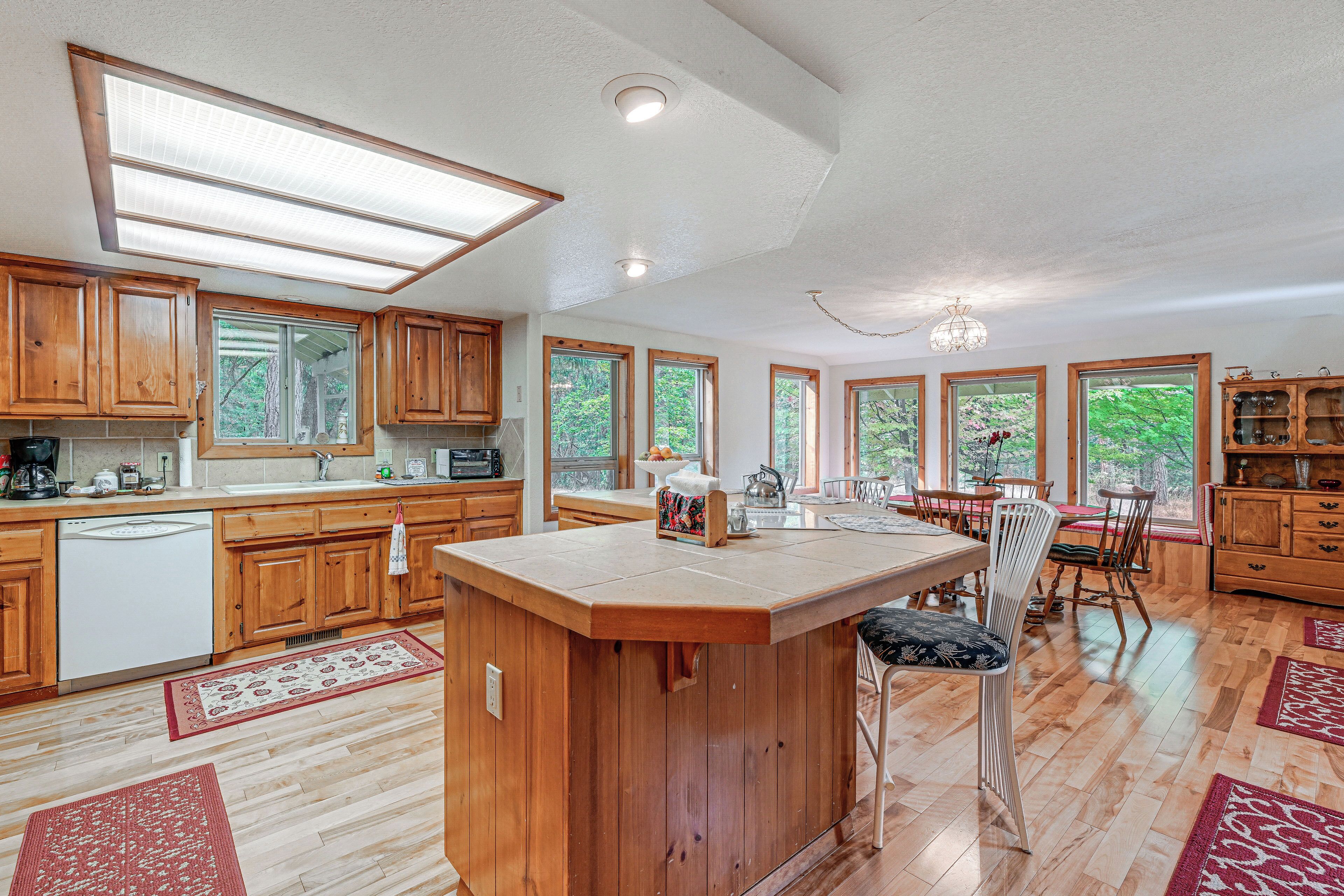 A spacious kitchen with wooden cabinets, a central island, and large windows.