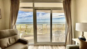 Habitación de hotel con un amplio ventanal corredero que da a un balcón con vista a la playa y al océano.