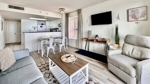 Una sala de estar moderna con un sofá, una mesa de centro y un televisor montado en la pared.
