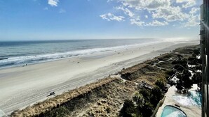 Vista a la playa con zona de piscina y un edificio al frente.