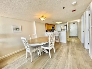 Una cocina moderna con armarios blancos, una mesa de comedor de madera y sillas.