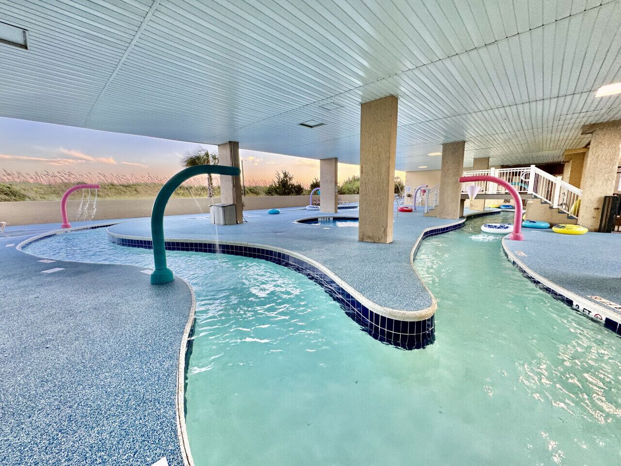 An indoor pool area with multiple lanes, concrete pillars, and a covered ceiling.