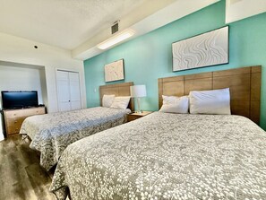 A hotel room with two beds, a television, and artwork on the walls.