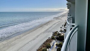 A beachfront view from a balcony with a clear sky, a sandy beach, and a calm sea. - Right next to family Kingdom! Oceanfront 1br full kitchen washer/dryer 1107 (Myrtle Beach)