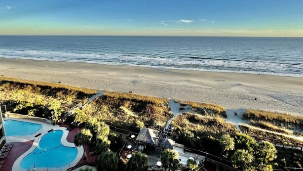 A beachfront property with a swimming pool, a small building, and a view of the ocean. - Tropical Resort, Modern Beachfront Condo with amazing oceanfront views!! 1018 (North Myrtle Beach)