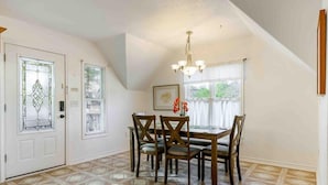 A dining area with a table and chairs, a chandelier, and patterned flooring.