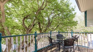 A wooden deck with a white picket fence, a table, and two chairs.