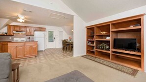 A spacious living area with a kitchen, dining area, and a large entertainment unit.