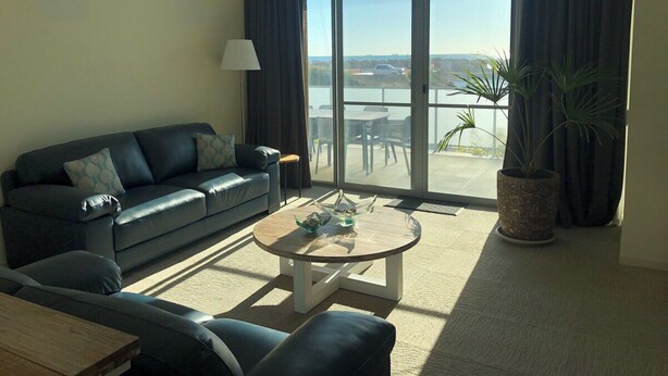 Ein modernes Wohnzimmer mit Sofa, Couchtisch und großen Fenstern mit Blick ins Freie.