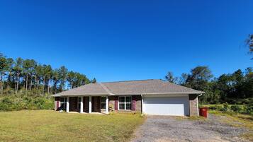 A single-story house with a covered porch, a garage, and a gravel driveway.
