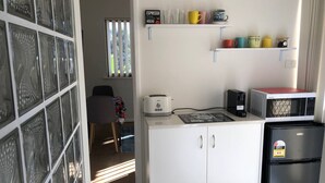 A compact kitchen with a toaster, a microwave, and a refrigerator. There are shelves above the counter holding various kitchenware. - Marina Retreat Geraldton - Centrally Located in Garden Setting (Beresford)