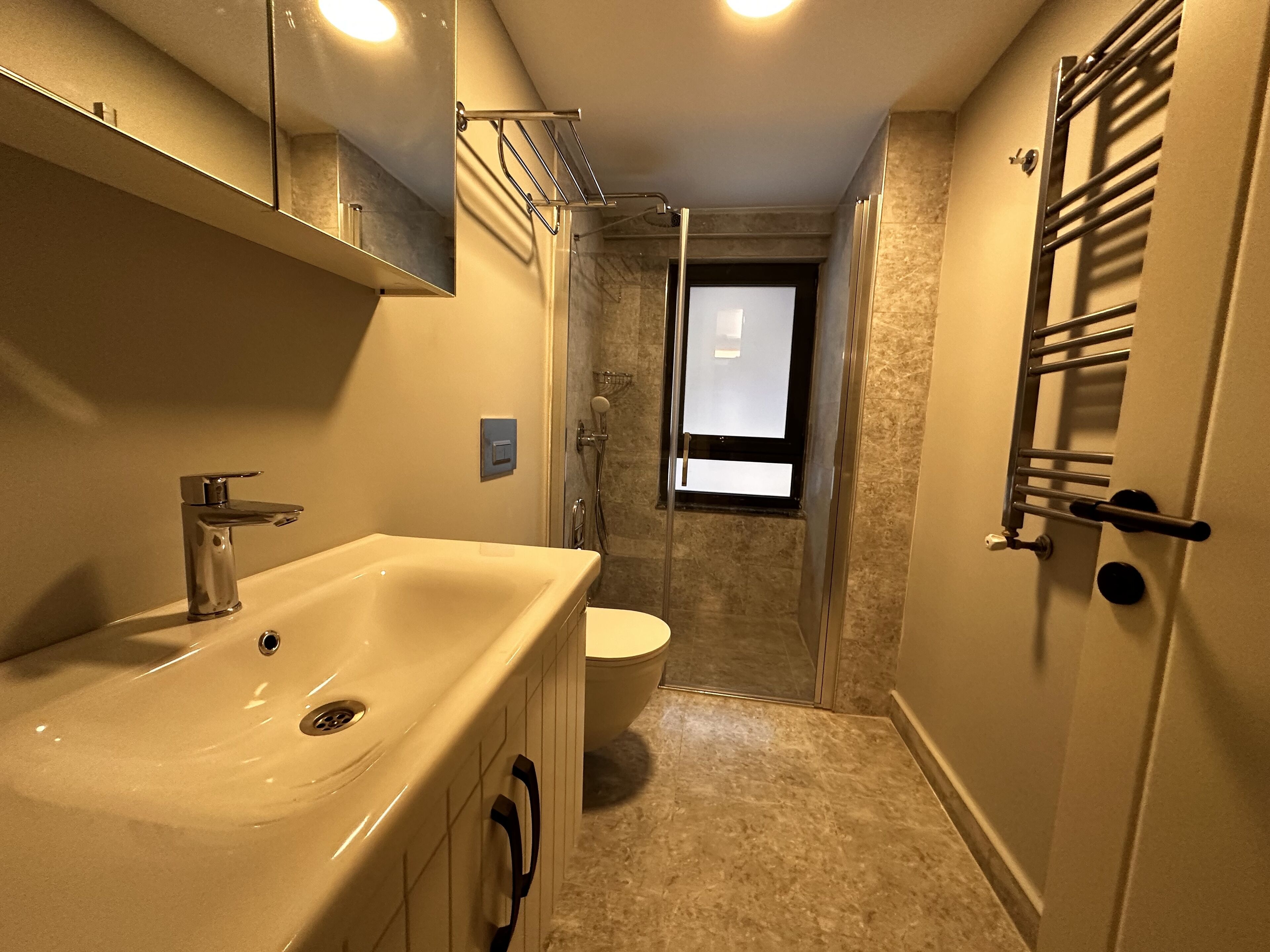A bathroom with a sink, mirror, shower, and toilet.