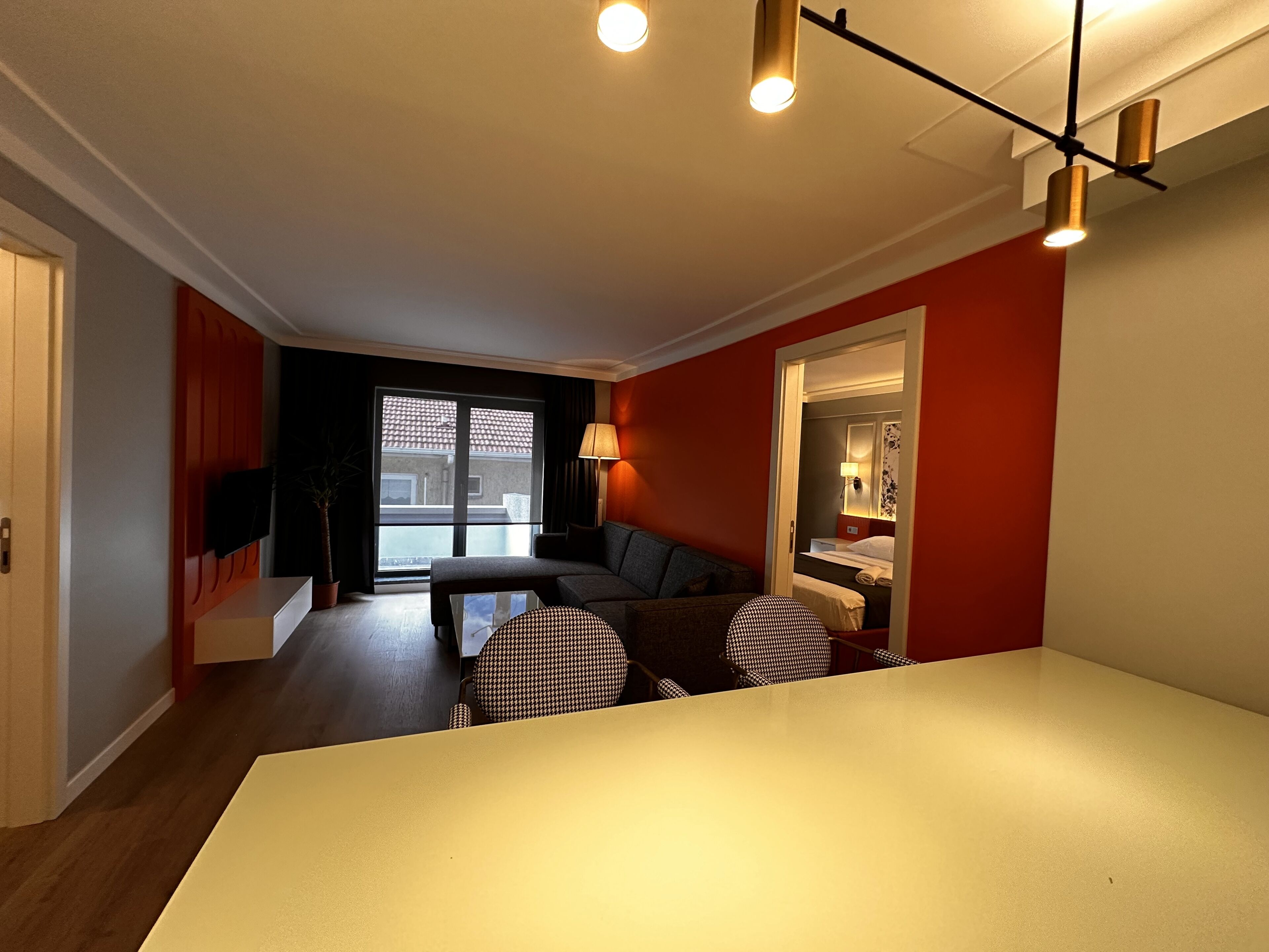 A modern living room with a sofa, a dining table, and a large window.
