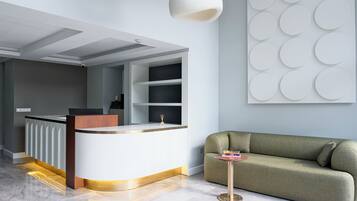 A modern reception area with a curved counter, a green sofa, and a decorative wall panel.