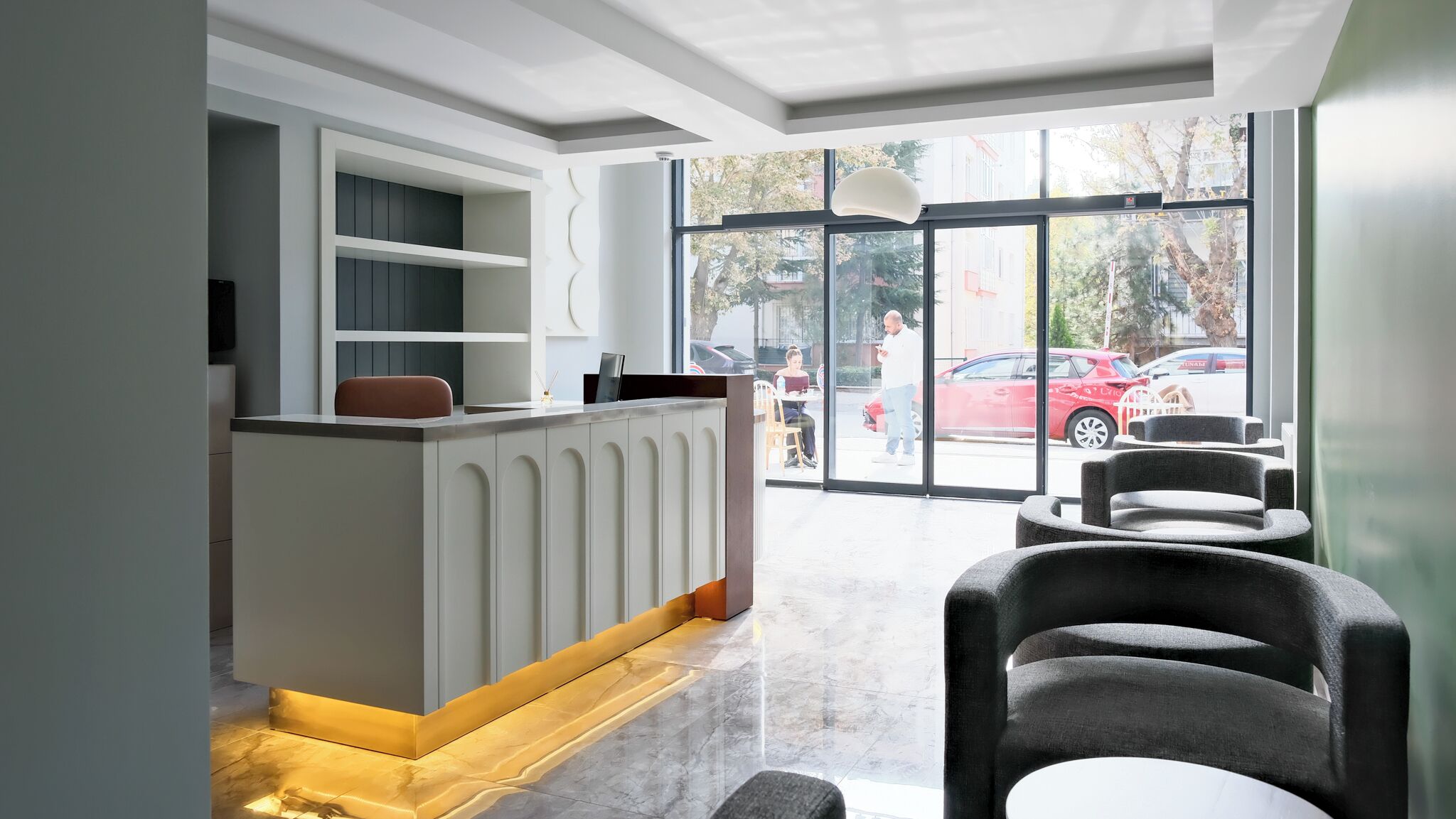 A modern reception area with a counter, seating, and large windows offering a view of the street.