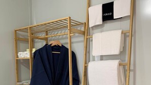 A wooden wardrobe with multiple shelves, a hanging robe, and neatly folded towels. - The Bower (Paynes Crossing)