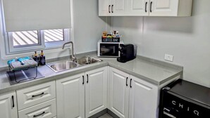 A compact kitchen with white cabinets, a coffee bar, and a black appliance labeled "CHIQ". - The Bower (Paynes Crossing)