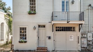 A two-story building with a front door, a small balcony with a railing, and a sign indicating a loading zone.
