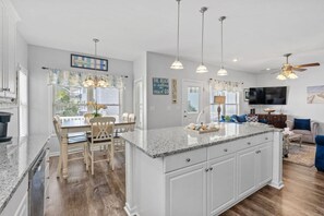 A kitchen with a large island, white cabinetry, and pendant lighting.