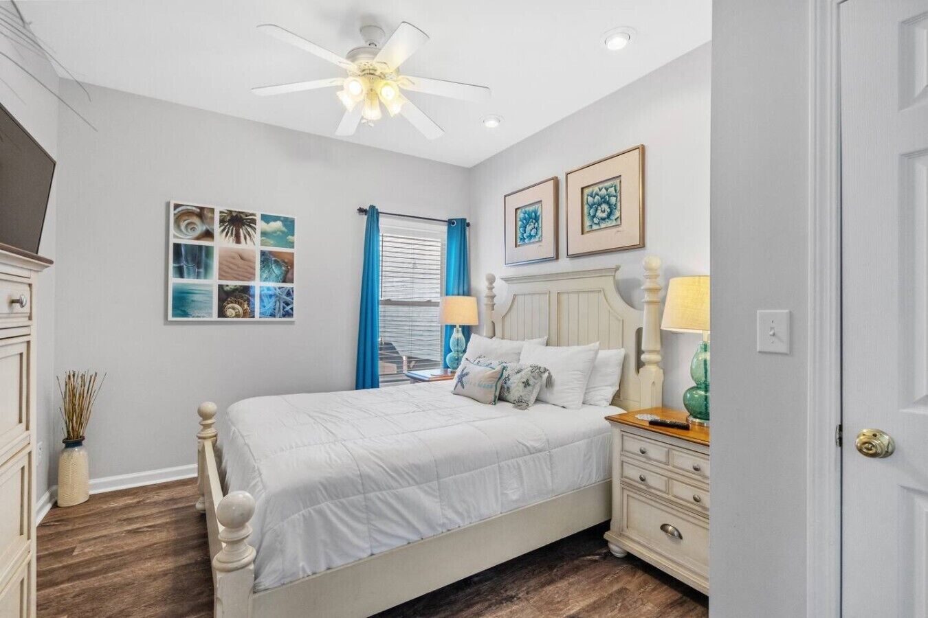 A bedroom with a bed, bedside tables, a ceiling fan, and artwork on the walls.